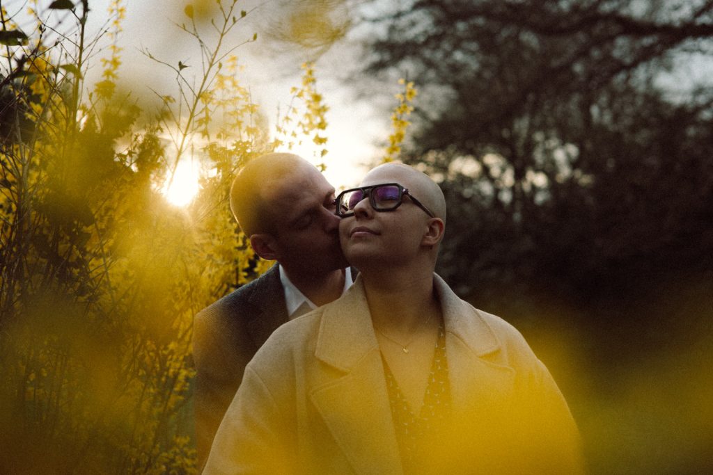 Moment intime entre un couple au coucher du soleil avec des forsythia au premier plan lors d'une séance engagement en Moselle