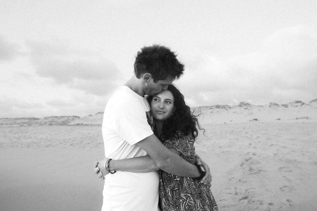 Couple qui s'enlace sur la plage pendant une séance engagement à Lacanau Océan