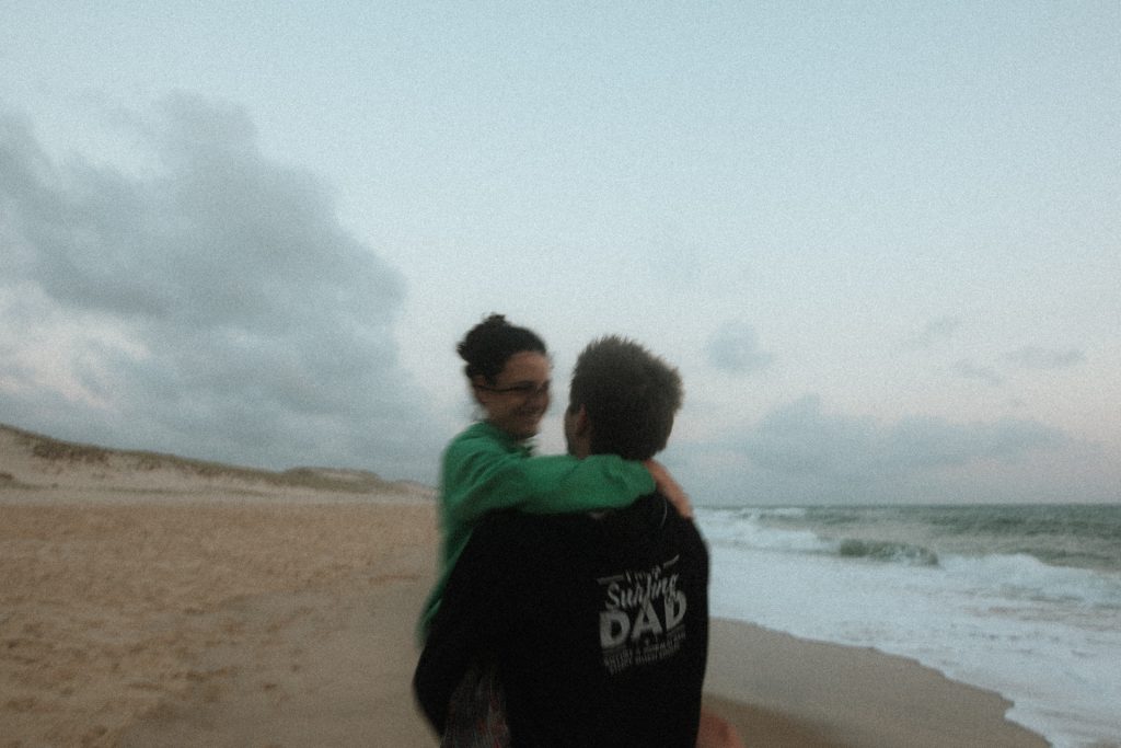 Couple qui s'enlace sur la plage pendant une séance engagement à Lacanau Océan