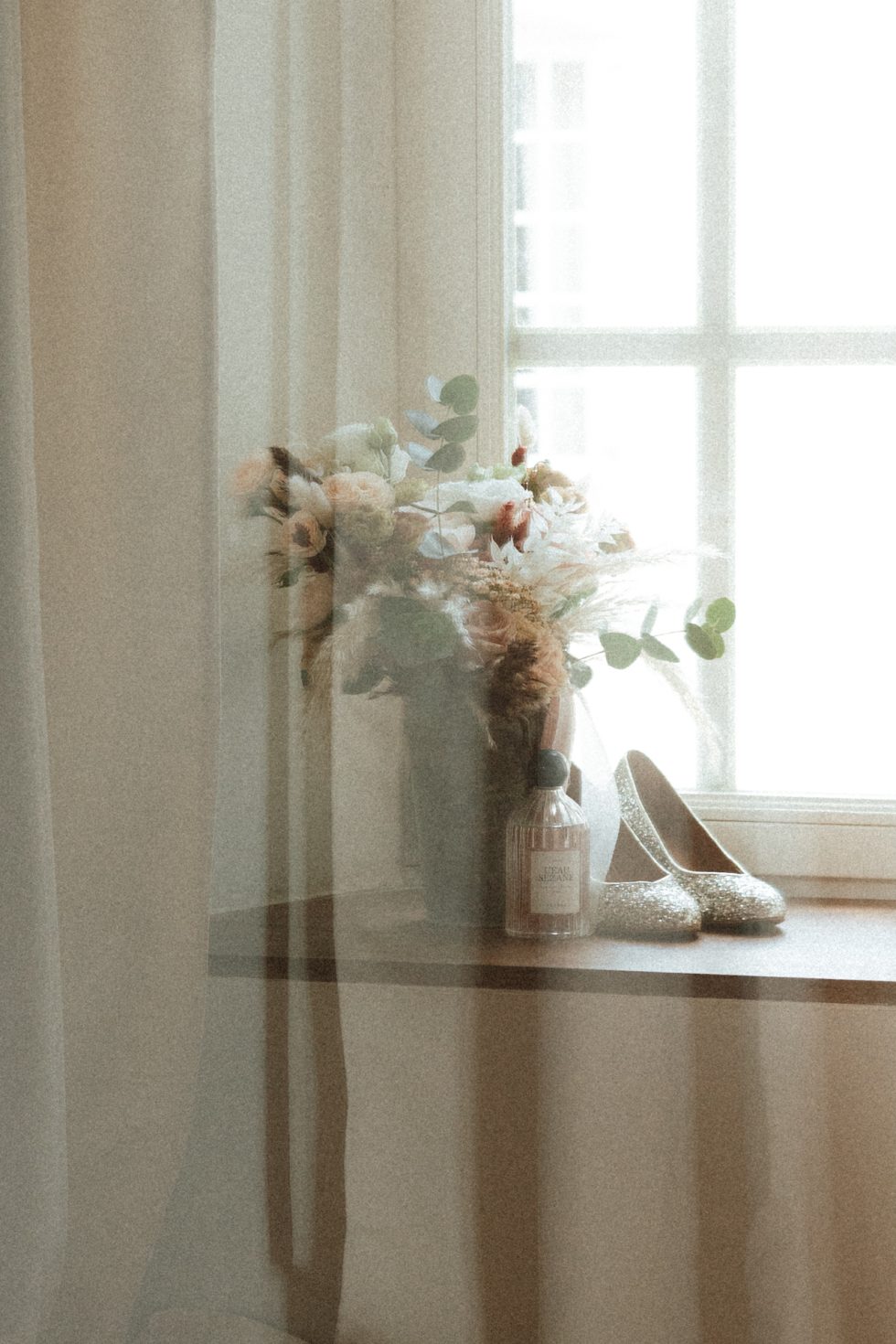 Mise en scène artistique avec un bouquet, un flacon de parfum et des chaussures pendant un mariage
