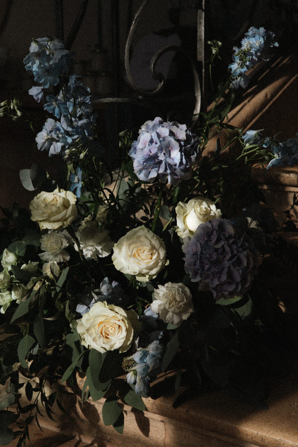 Un bouquet de roses blanches et hortensias bleues dans un jeu d'ombre et lumière au Château d'Art-sur-Meurthe