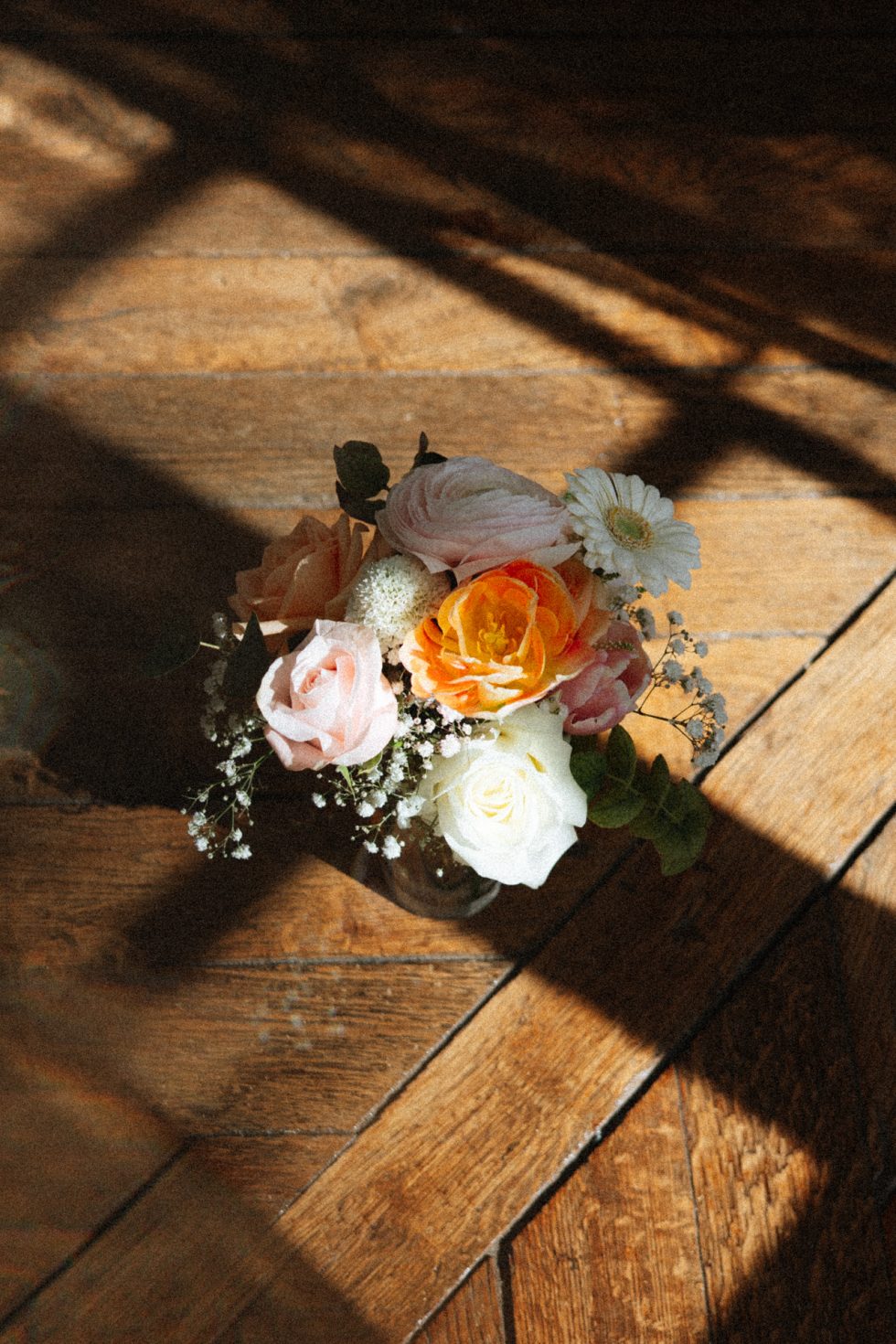 Un bouquet dans un vase posé sur le parquet du Château de Vandeléville. Le bouquet est baigné par la lumière qui passe par la fenêtre
