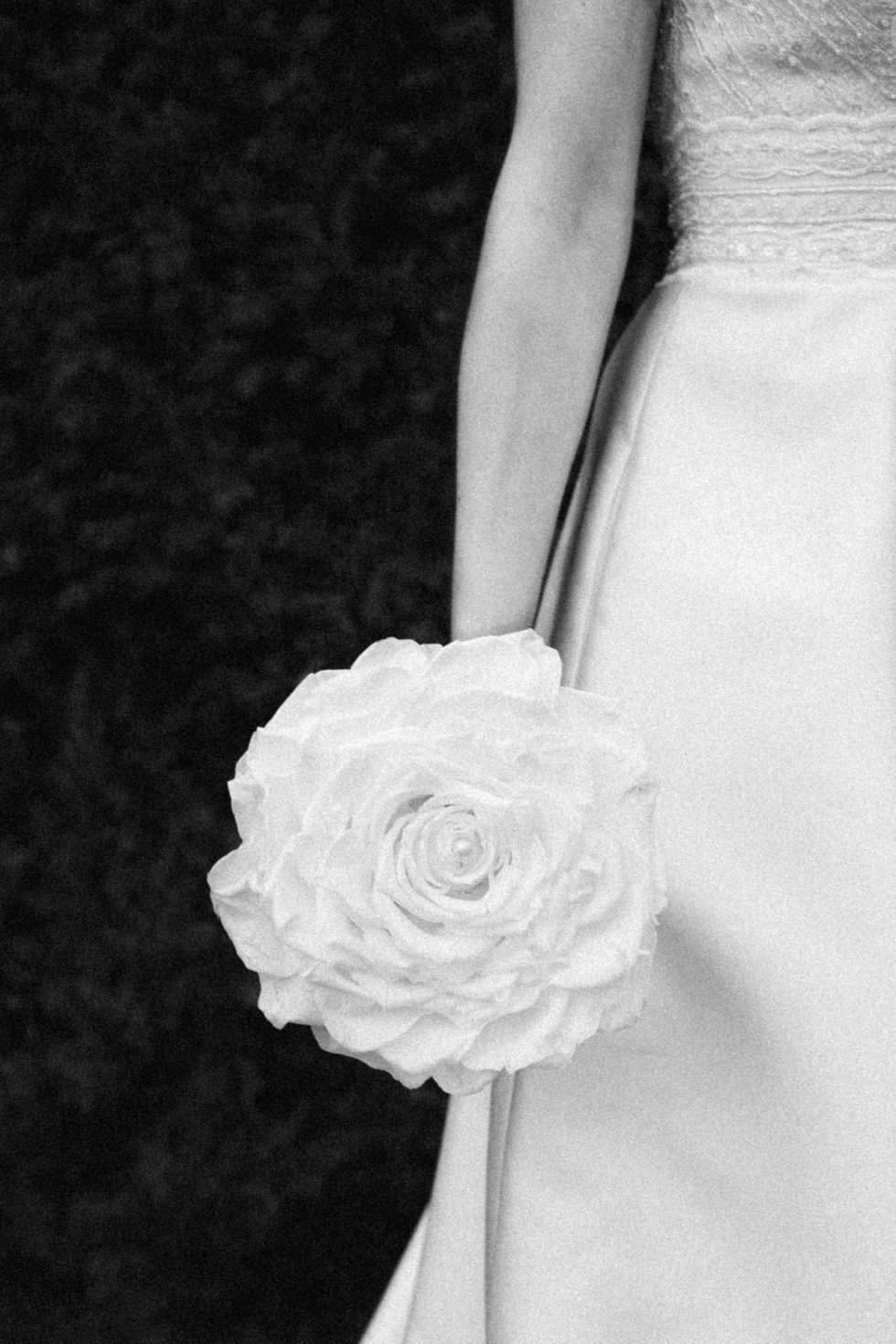 Plan coupé d'une mariée tenant une grosse rose éternelle au Domaine du Feyel