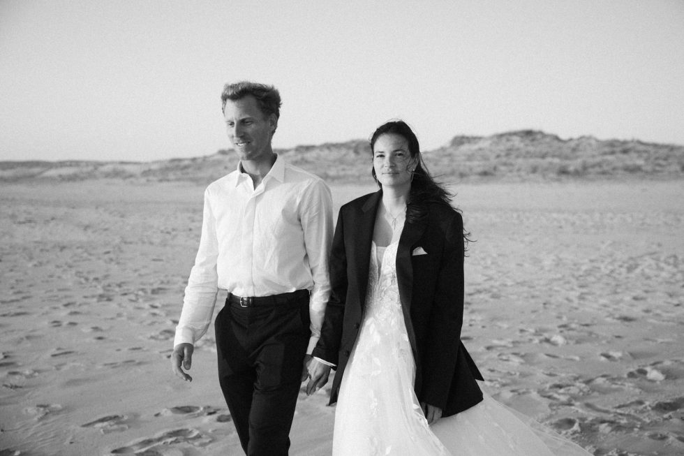 Séance jeunes mariés sur la plage de Lacanau Océan . Les mariés marchent sur la plage en se tenant la main