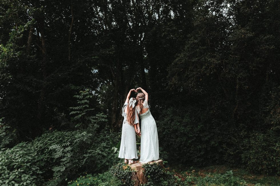 Les demoiselles d'honneur sont de dos, debout sur une souche d'arbre et forment un cœur avec leurs bras