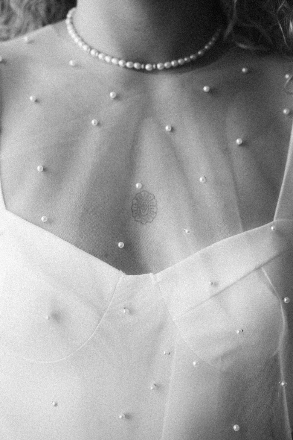 Détail de la robe de mariée ornée de perles. Photographie de mariage élégante et minimaliste.