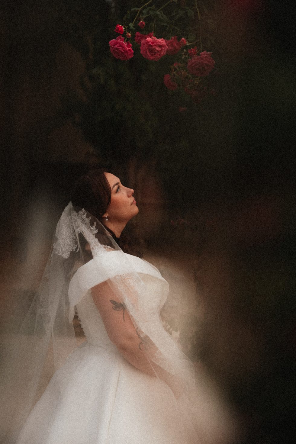 Portrait romantique d'une mariée à Metz. Elle est de profil et regarde des roses au dessus d'elle.