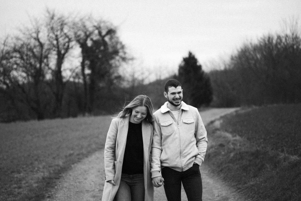 Couple qui marche en se tenant la main lors d'une séance engagement dans un champ à Corny-sur-Moselle