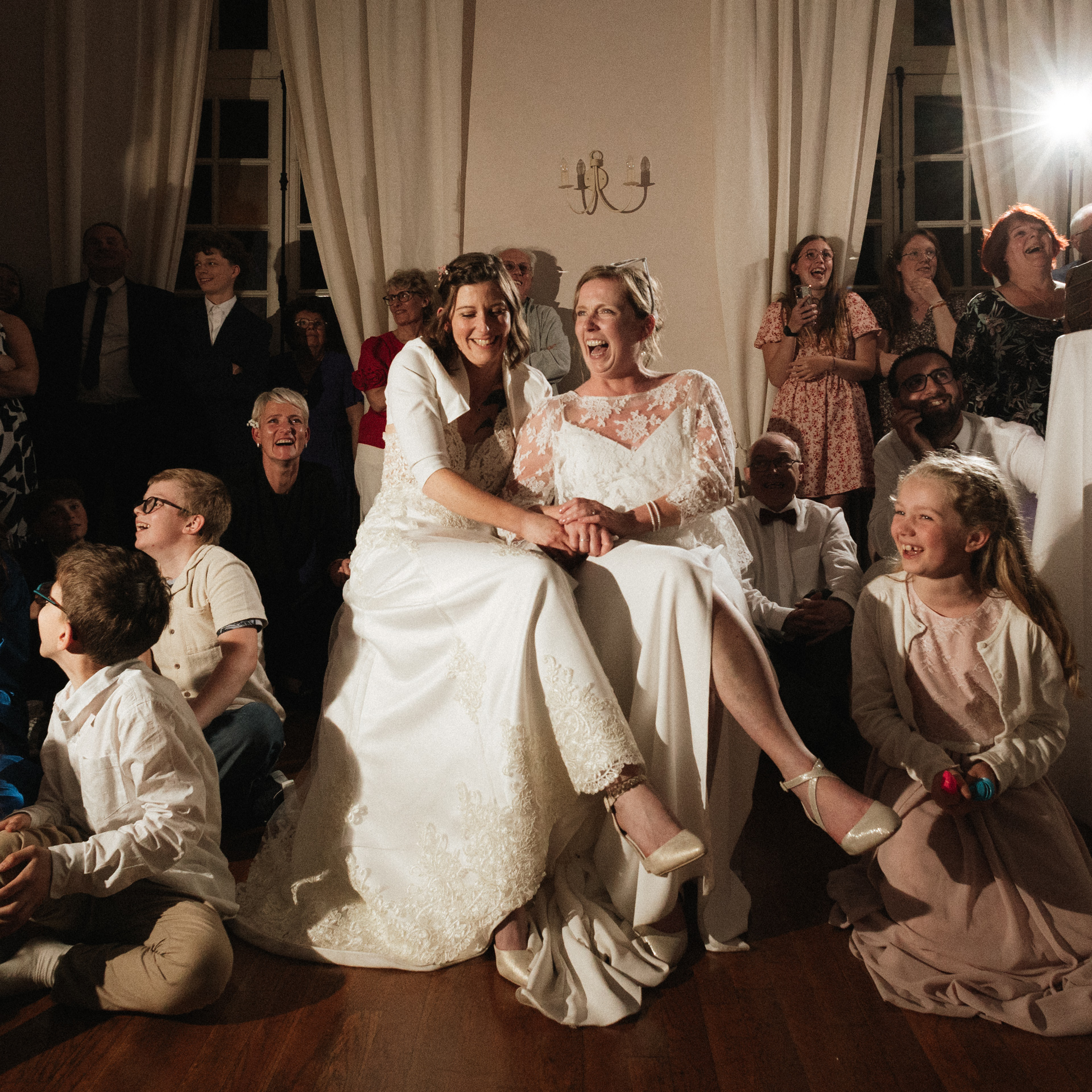 Les mariées et leurs invités rigolent pendant le passage du diaporama au Château de Vandeléville