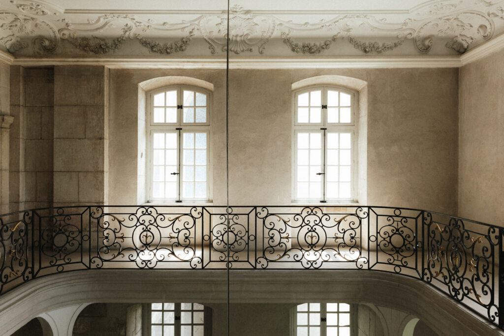 Balcon intérieur de l’Abbaye des Prémontrés avec garde-corps en fer forgé, grandes fenêtres lumineuses et moulures décoratives élégantes