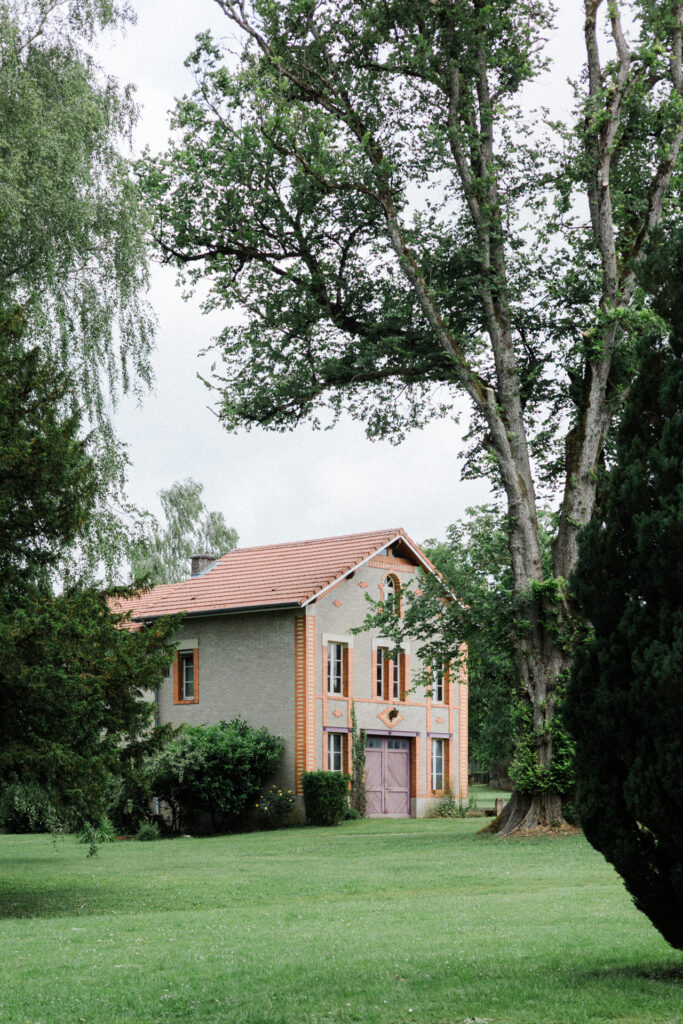 Gîte du Château des Aulnes avec façade claire et briques rouges, toiture en tuiles et jardin arboré dans un cadre paisible
