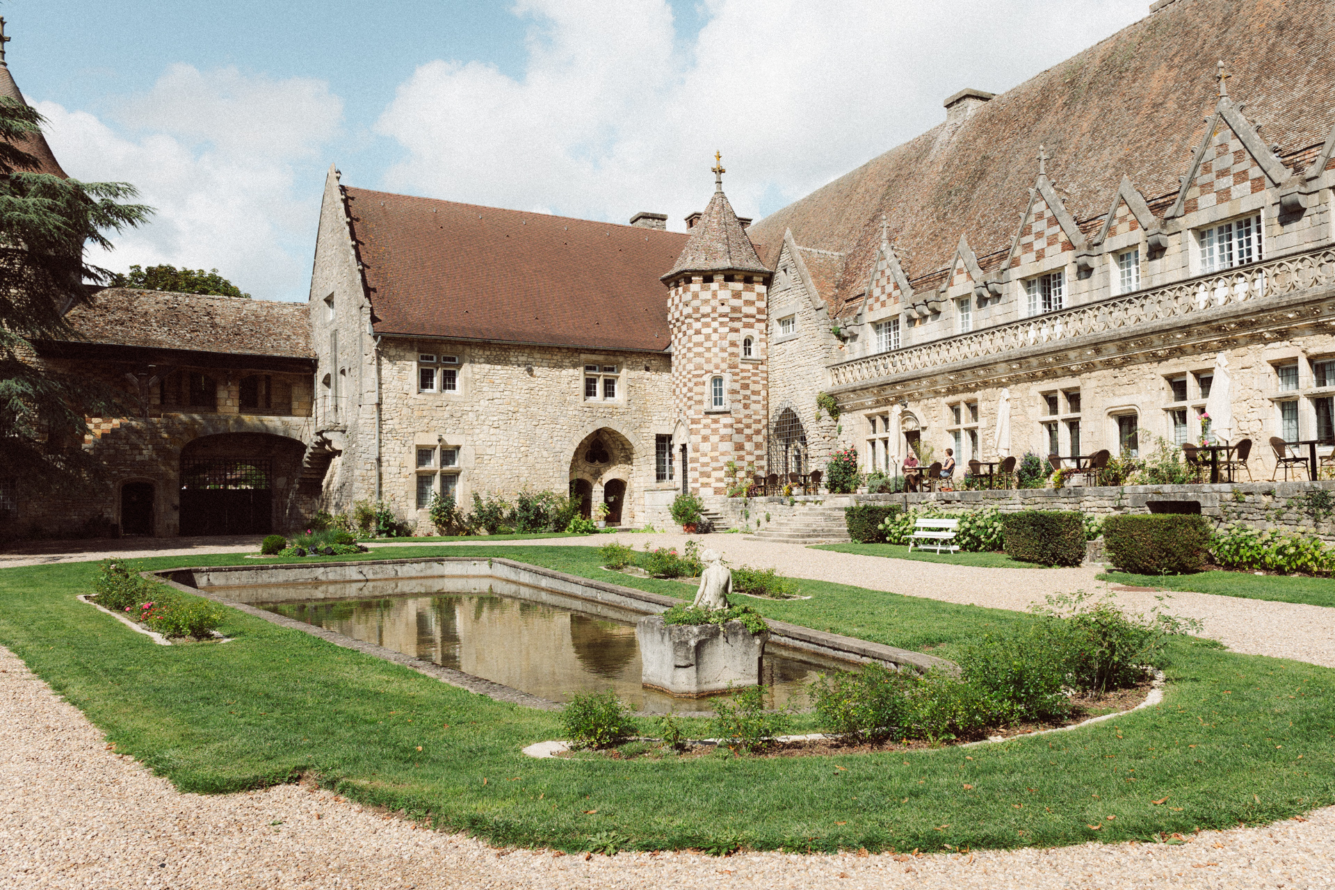 Extérieur du Château d’Hattonchâtel avec cour, bassin et architecture historique en pierre dans un cadre verdoyant