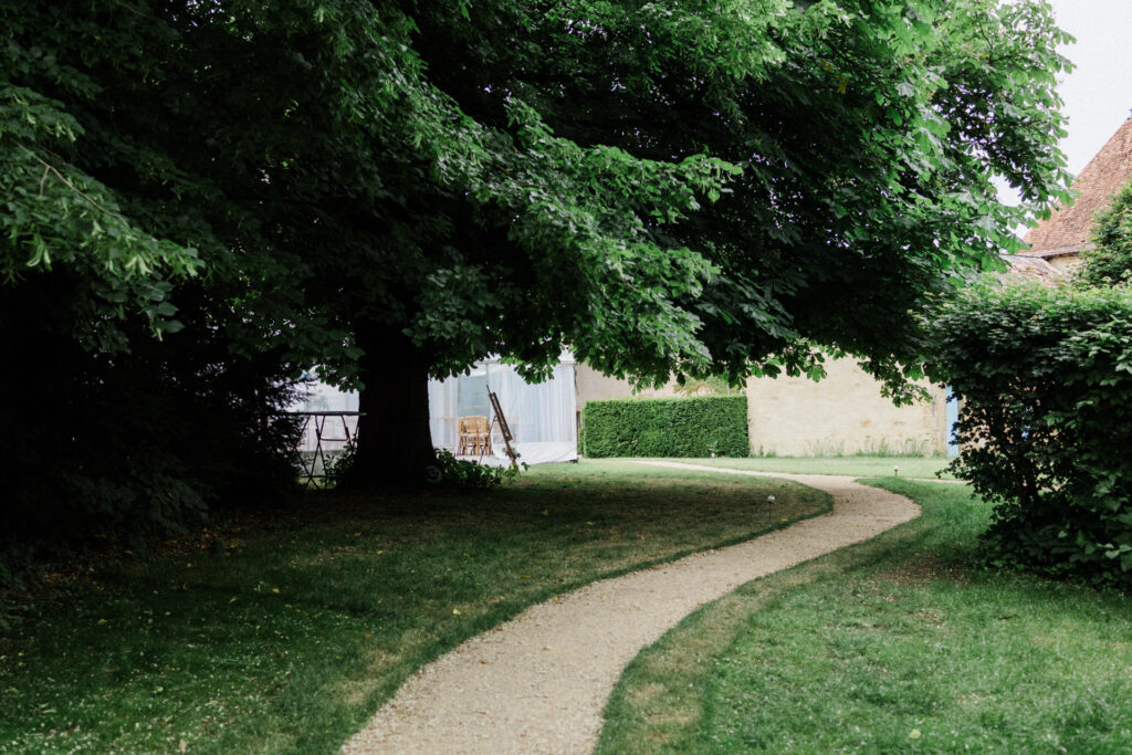 Jardin du Château de Jaulny avec allée sinueuse, pelouse verdoyante et grands arbres offrant une atmosphère paisible