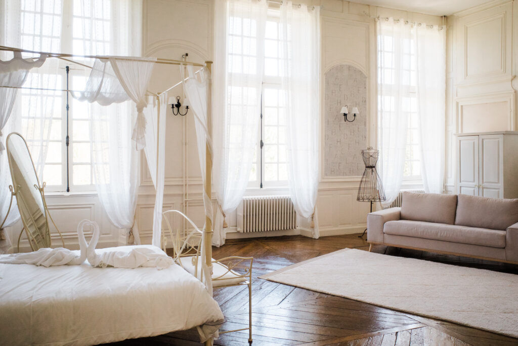 Chambre lumineuse au Château de Vandeléville avec lit à baldaquin, voilages et décoration élégante de mariage