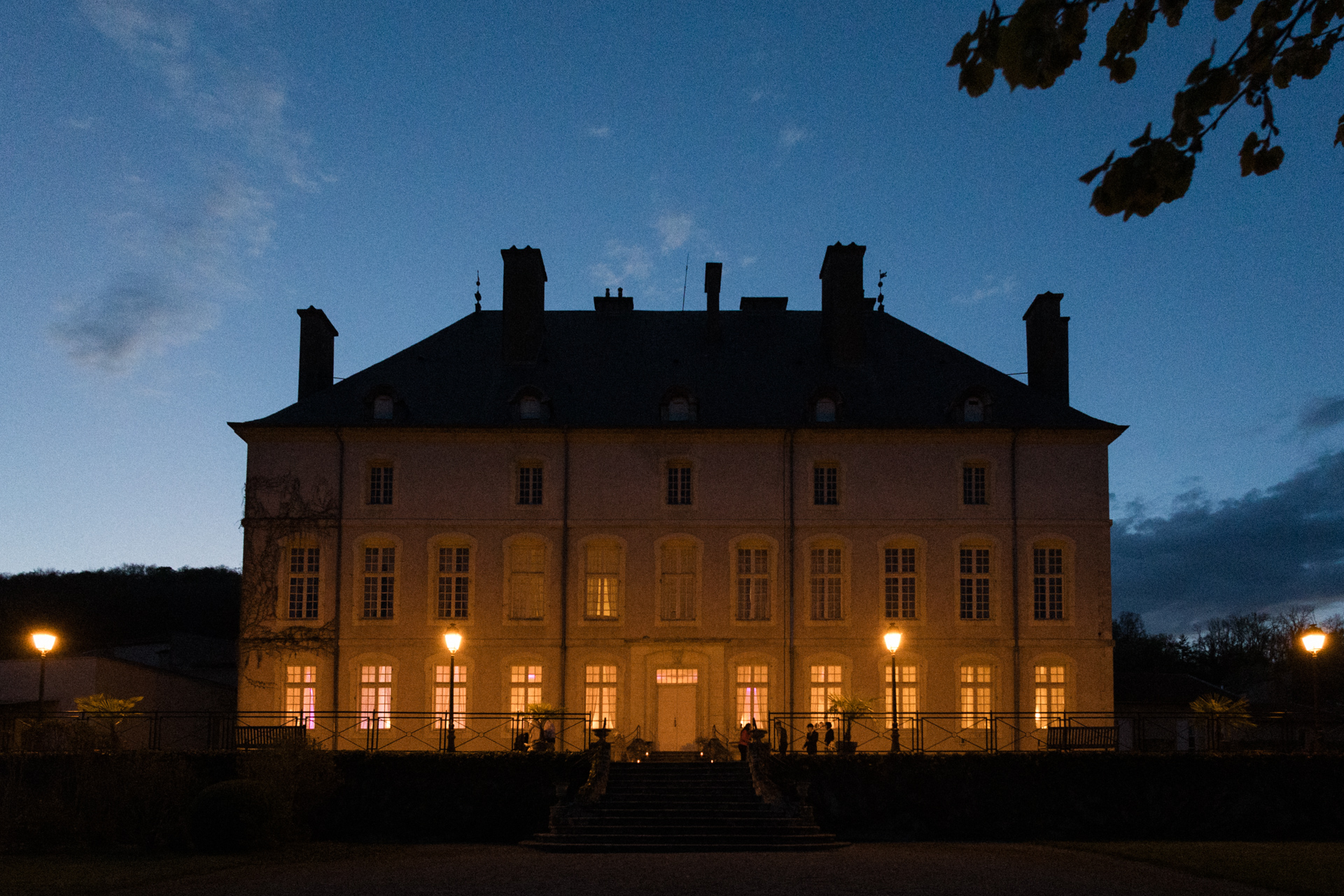 Façade du Château de Vandeléville illuminée de nuit, atmosphère chaleureuse pendant une réception de mariage