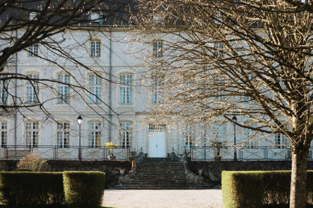 Façade lumineuse du Château de Vandeleville avec escaliers centraux et jardin structuré au premier plan