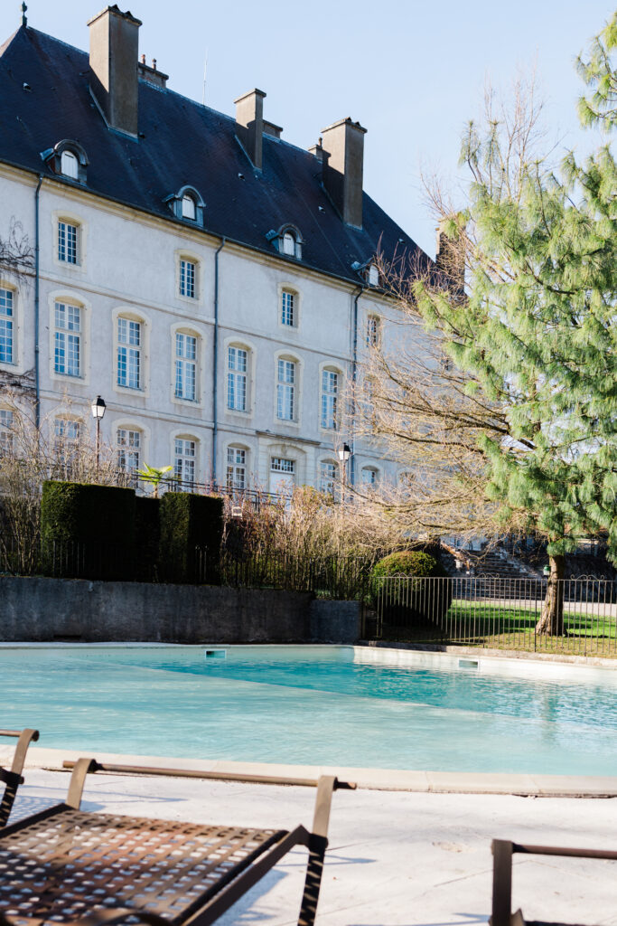 Piscine extérieure du Château de Vandeléville avec transats et vue sur le bâtiment historique