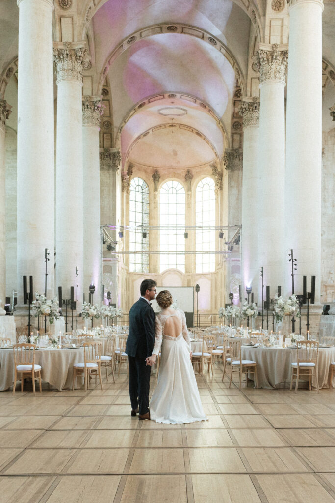 Mariés main dans la main dans la salle abbatiale de l’Abbaye des Prémontrés, décorée pour une réception élégante
