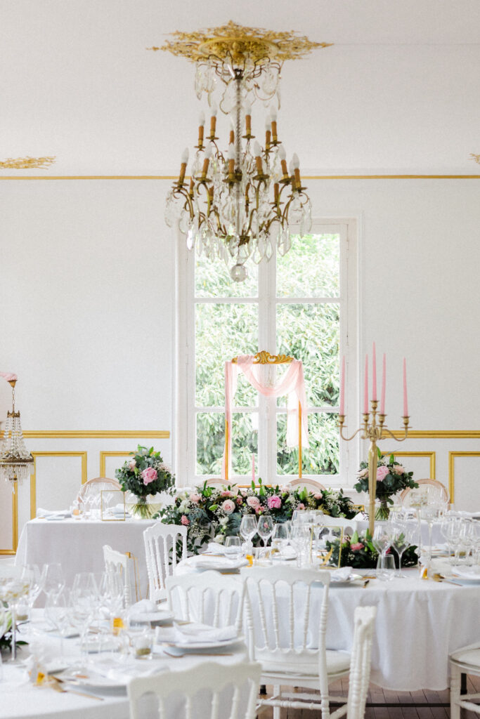 Salle de réception élégante avec tables dressées, lustre et décor floral dans le Château des Aulnes