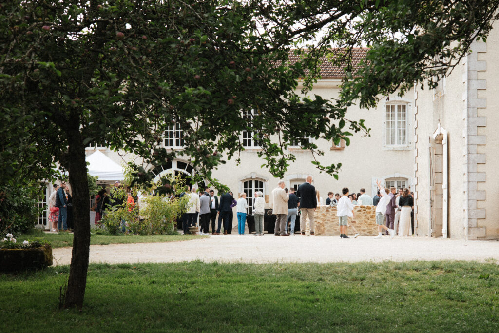 Invités rassemblés dans la cour du Château Ferme d’Aboncourt autour d’un espace cocktail extérieur de mariage.