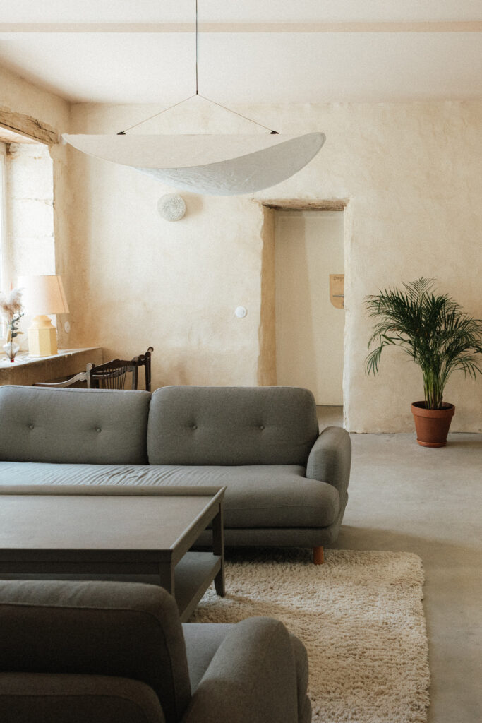 Salon cosy du Château-Ferme d’Aboncourt avec un canapé moderne, tapis clair et ambiance chaleureuse