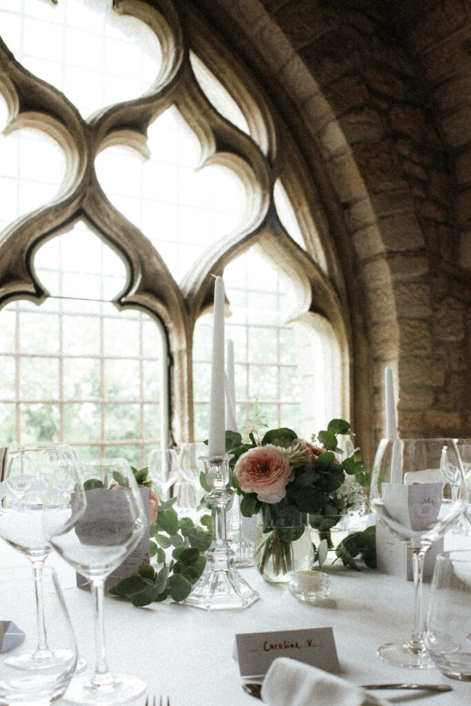 Table élégante dressée avec centre floral et bougies devant une fenêtre gothique au Château de Hattonchâtel