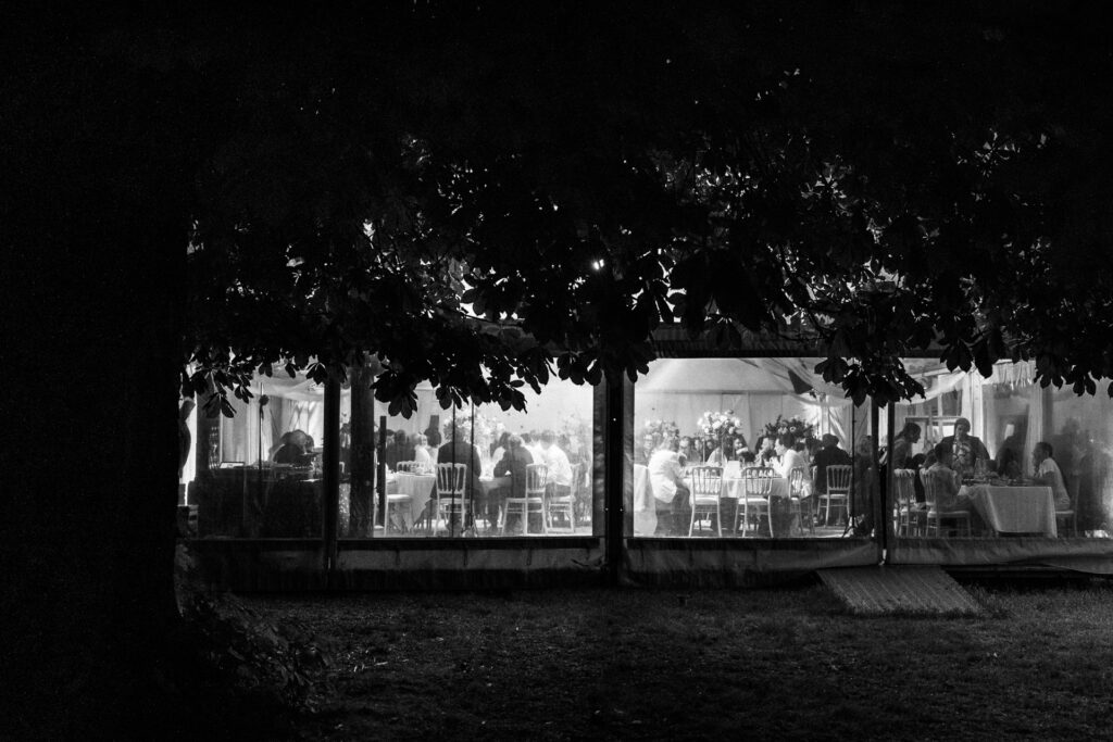Réception de mariage de nuit sous chapiteau avec invités attablés et ambiance lumineuse au Château de Jaulny