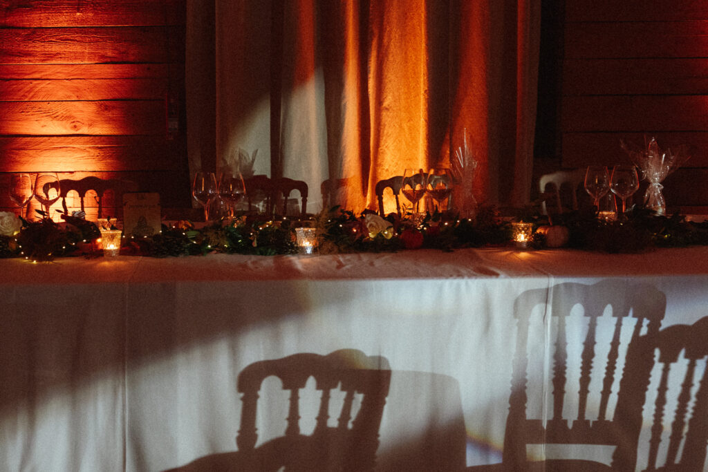 Table de mariage décorée au Domaine de Raville avec bougies, fleurs et ambiance chaleureuse en lumière tamisée.