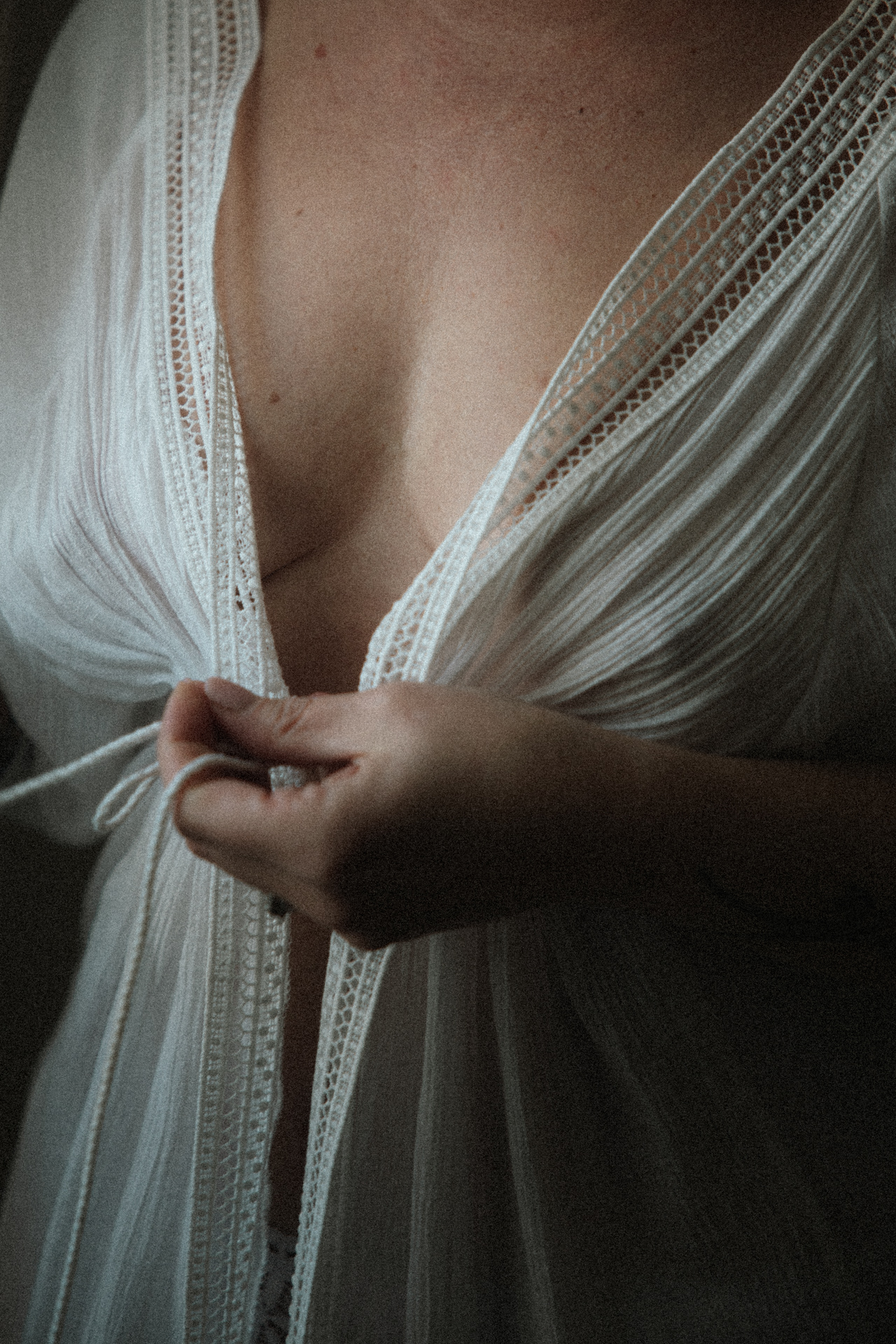 Séance boudoir de la mariée, détail d’un déshabillé blanc délicat dans une lumière douce.