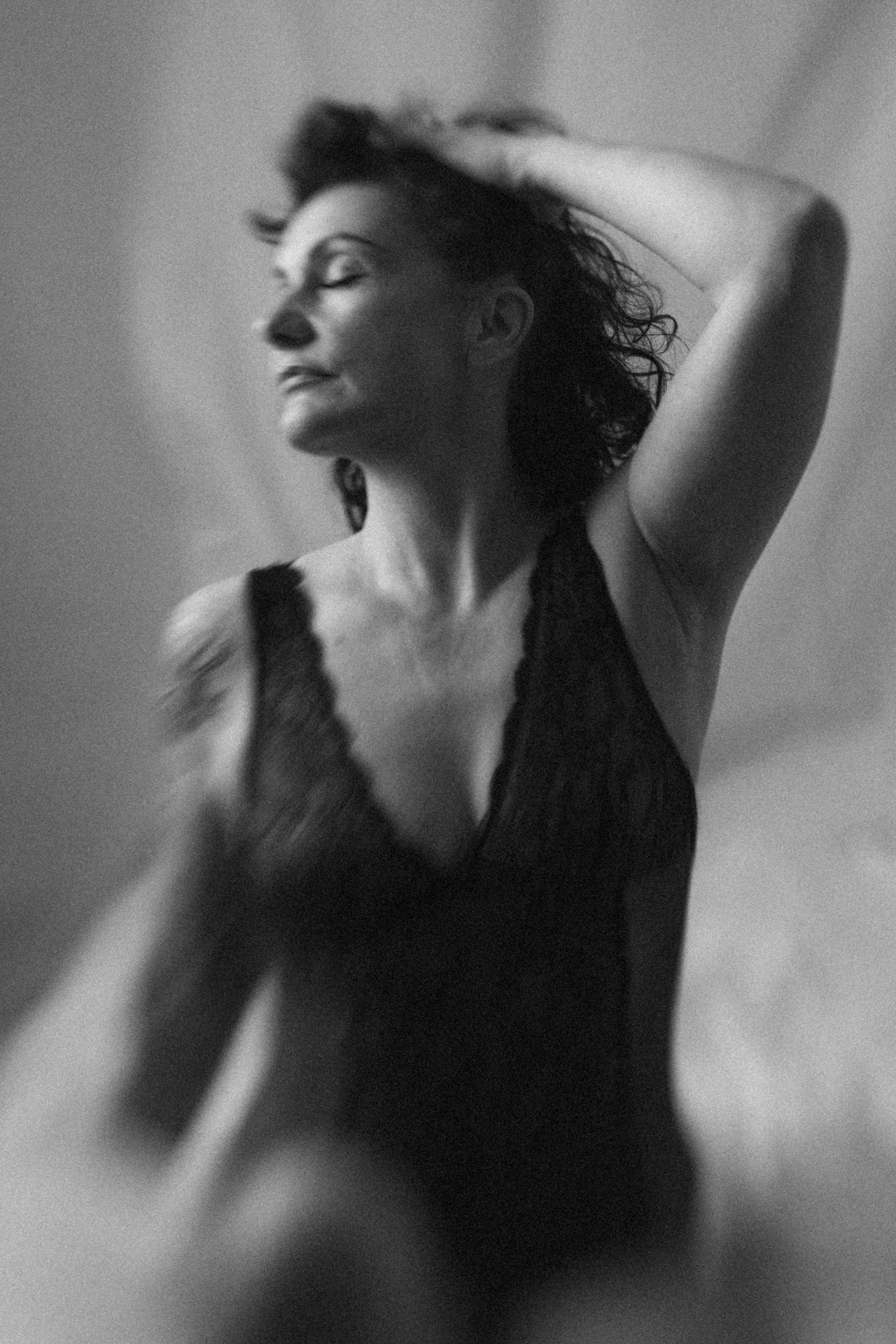 Séance boudoir à Metz en noir et blanc, portrait flou d’une femme en body noir dans une ambiance douce.