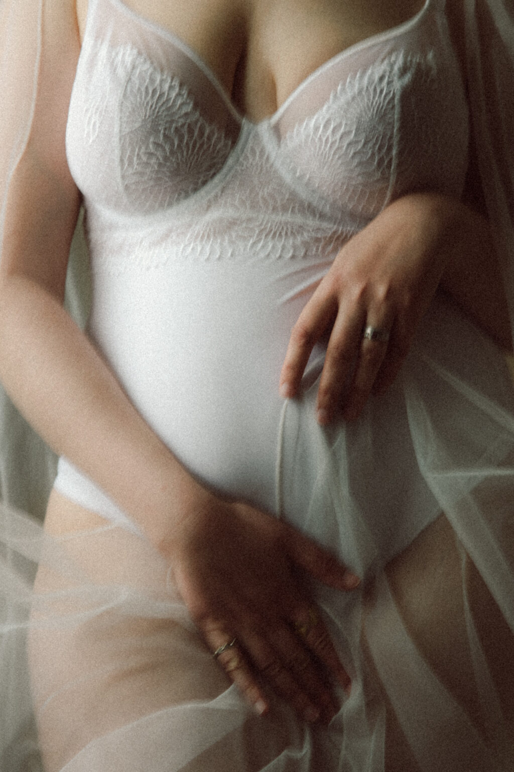 Mariée en lingerie blanche et voile léger, capturée pendant une séance boudoir de la mariée