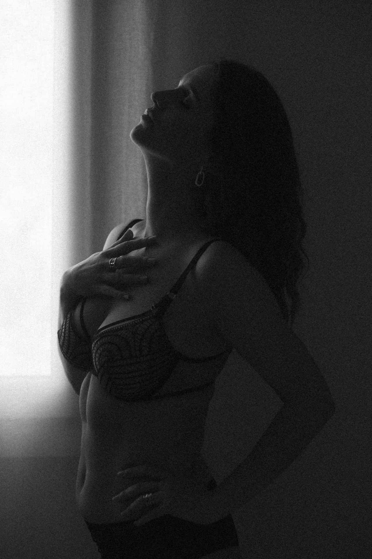 Séance boudoir à Metz en lingerie noire, silhouette féminine près d’un rideau lumineux dans une ambiance artistique.