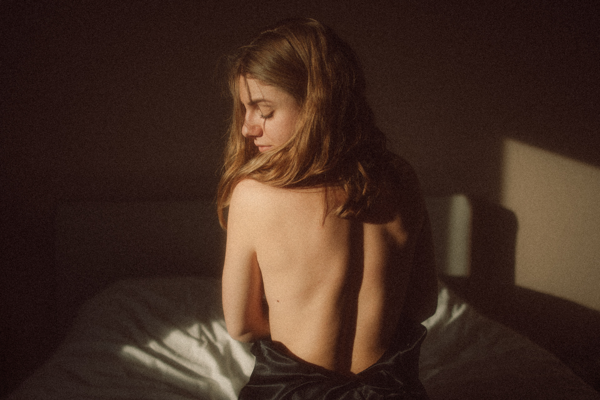 Séance boudoir en Moselle avec détail du dos nu dans une lumière sombre et intime.