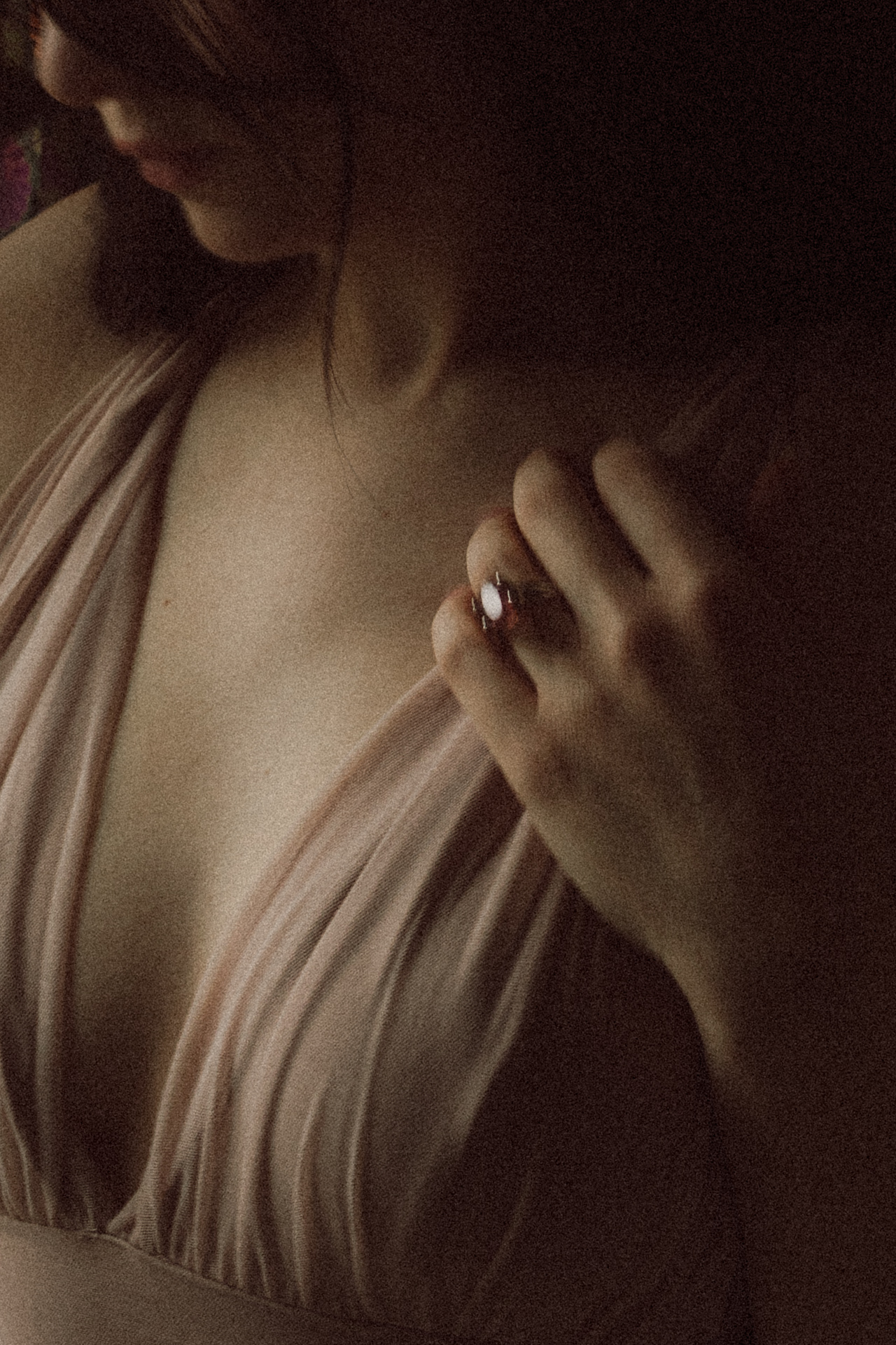 Détail sensuel d’une femme ajustant son body en tissu plissé, avec une bague visible à la main. Séance boudoir à Metz