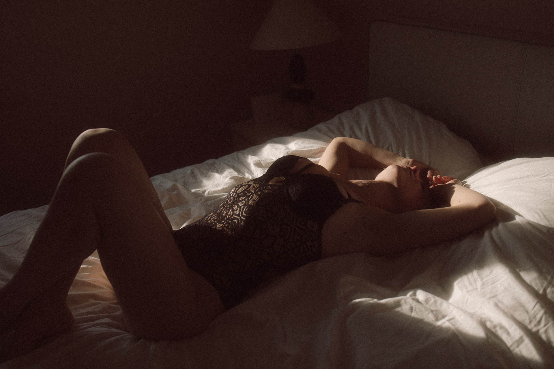 Séance boudoir en Lorraine en lingerie noire, silhouette allongée devant une fenêtre en noir et blanc.