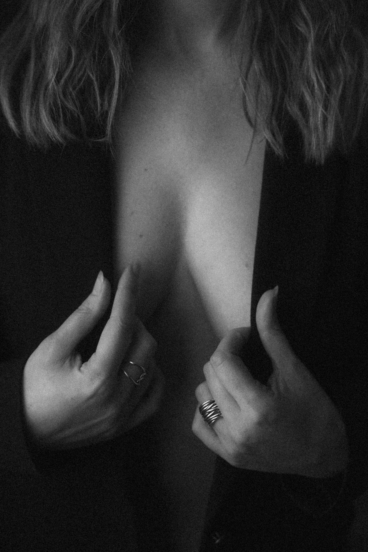 Séance boudoir en Moselle en noir et blanc, détail d'une femme tenant son blazer pour mettre en valeur son décolleté.